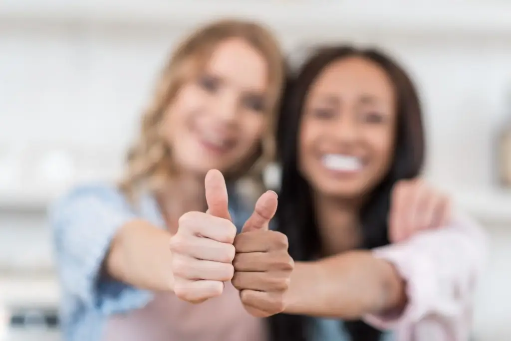 close up of young multiethnic waitresses smiling and showing thumbs up